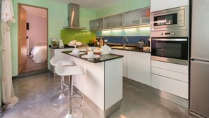 A modern kitchen with a central island, stainless steel appliances, and a view of the sea through a window. - Beautiful private villa for 6 guests with WIFI, A/C, TV and patio (Manacor)