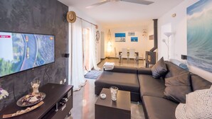 A modern living room with a flat-screen TV, a ceiling fan, a sofa, and a dining area with chairs and a table. - Beautiful private villa for 6 guests with WIFI, A/C, TV and patio (Manacor)