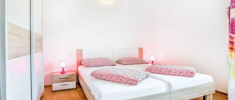 A bedroom with a double bed, two bedside tables with lamps, and a wooden floor.