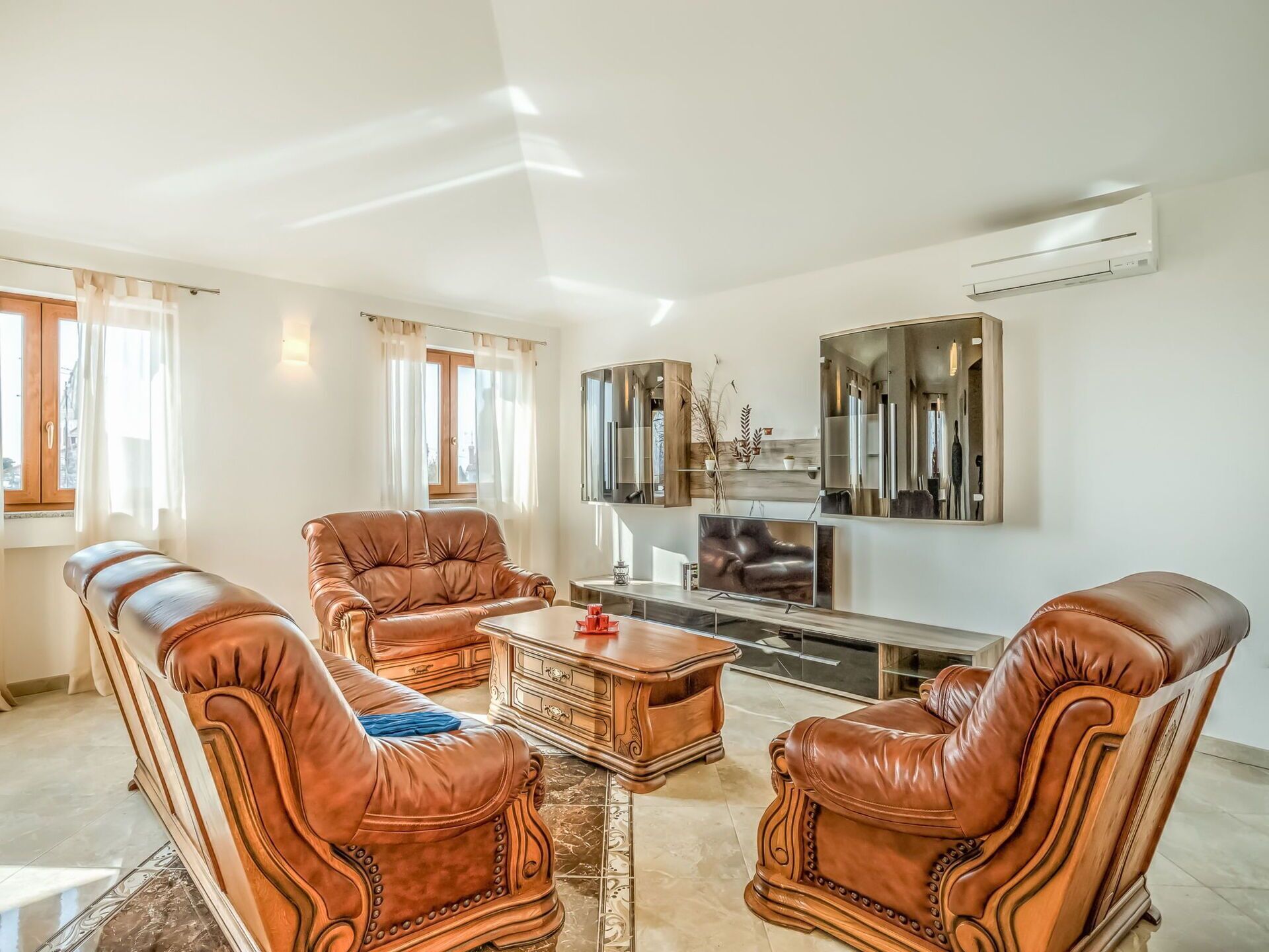 A living room with leather sofas, a coffee table, and a TV.