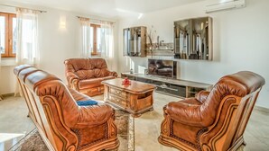 A living room with leather sofas, a coffee table, and a TV. - Beautiful apartment for 6 people with pool, WIFI, A/C, TV, terrace and pets allowed (Umag)