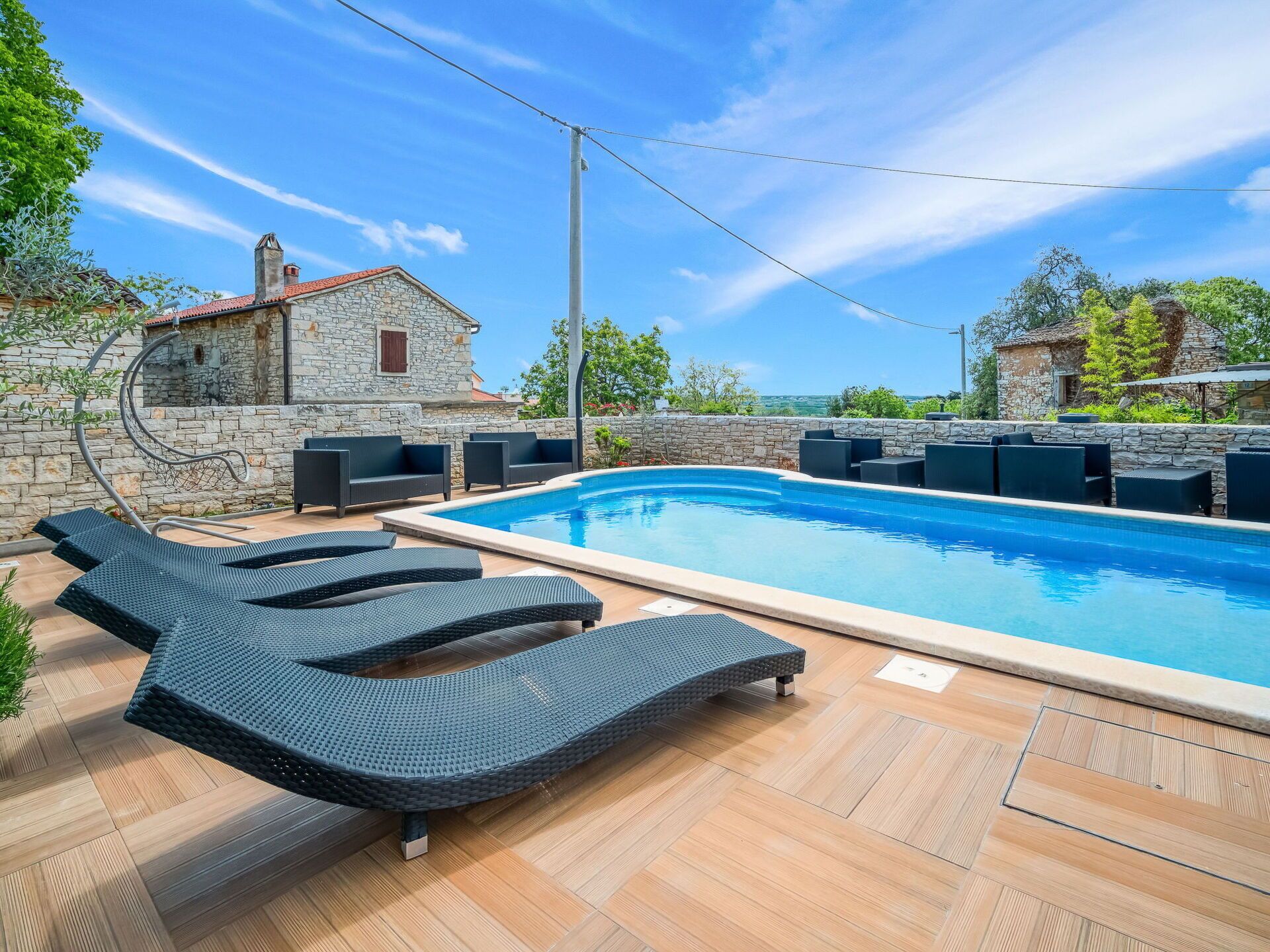 A swimming pool with lounge chairs, stone walls, and a stone building in the background.