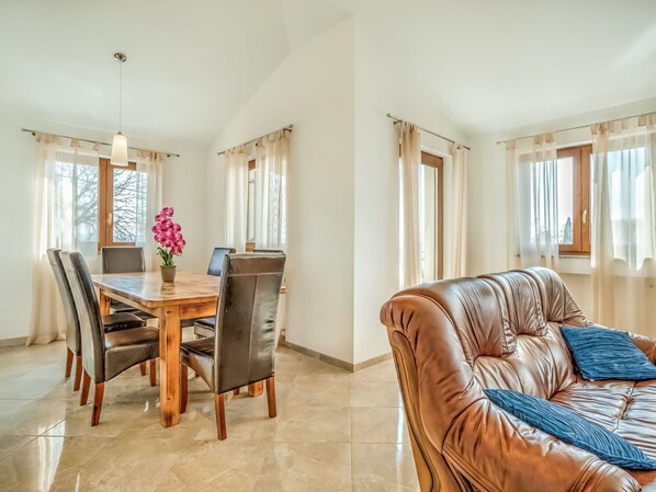 A dining area with a wooden table and chairs, a vase of flowers, and a laptop on the table. - Beautiful apartment for 6 people with WIFI, A/C, pool, TV, terrace and pets allowed (Umag)