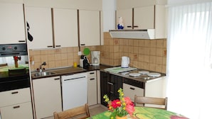 A compact kitchen with a stove, sink, and a small dining area with a table and chairs.