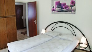 A bedroom with a bed, a wooden wardrobe, a door, and a wall-mounted picture.