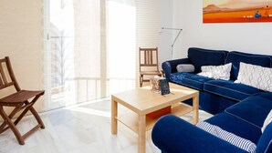 A modern living room with a blue sofa, wooden coffee table, and a painting on the wall.
