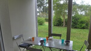 An outdoor patio with a table and chairs, surrounded by greenery. - Lovely apartment for 4 people with pool, WIFI, TV and terrace (Ondres)