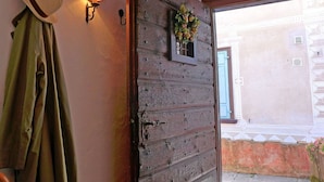 Une porte en bois rustique avec une plaque portant un numéro, un chapeau accroché au mur et une applique murale.