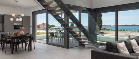 Et moderne interiør med en trappe op til en balkon med udsigt over stranden.