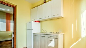 Eine kleine Küche mit weißen Schränken, einem integrierten Kühlschrank und einem Gasherd.