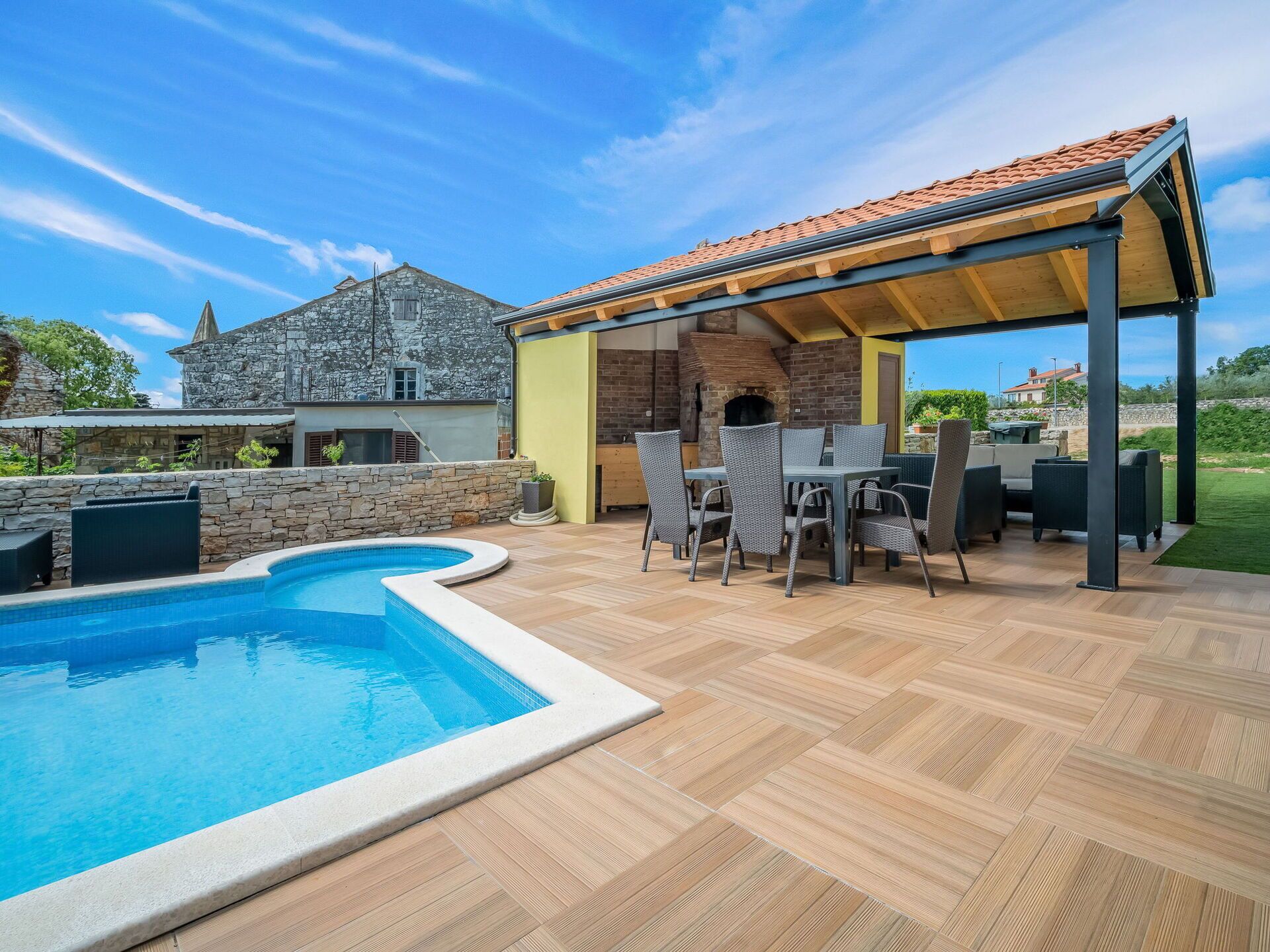 A backyard with a swimming pool, outdoor seating, and a stone building.