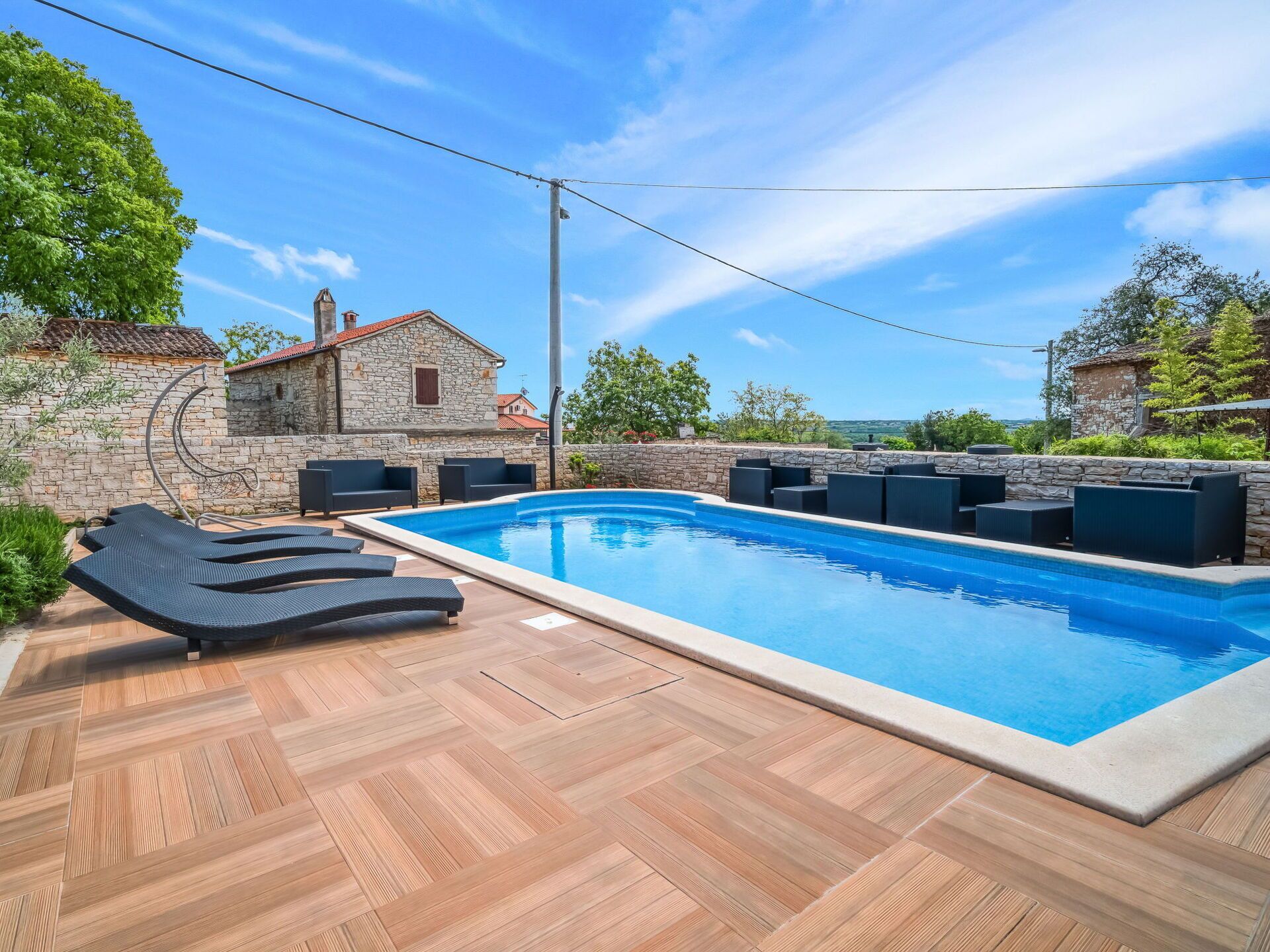 Una piscina con sillas de descanso y un muro de piedra.