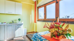 Ein Zimmer mit Küchenzeile, einem Esstisch mit floraler Dekoration und einem Fenster mit Blick nach draußen.