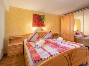Een hotelkamer met een houten bed, een nachtkastje, een spiegel en een schilderij aan de muur.