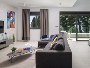 En moderne stue med sofa, sofabord, fjernsyn og et billede på væggen.
