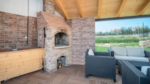 An outdoor kitchen area with a brick oven, a sink, and wicker furniture.