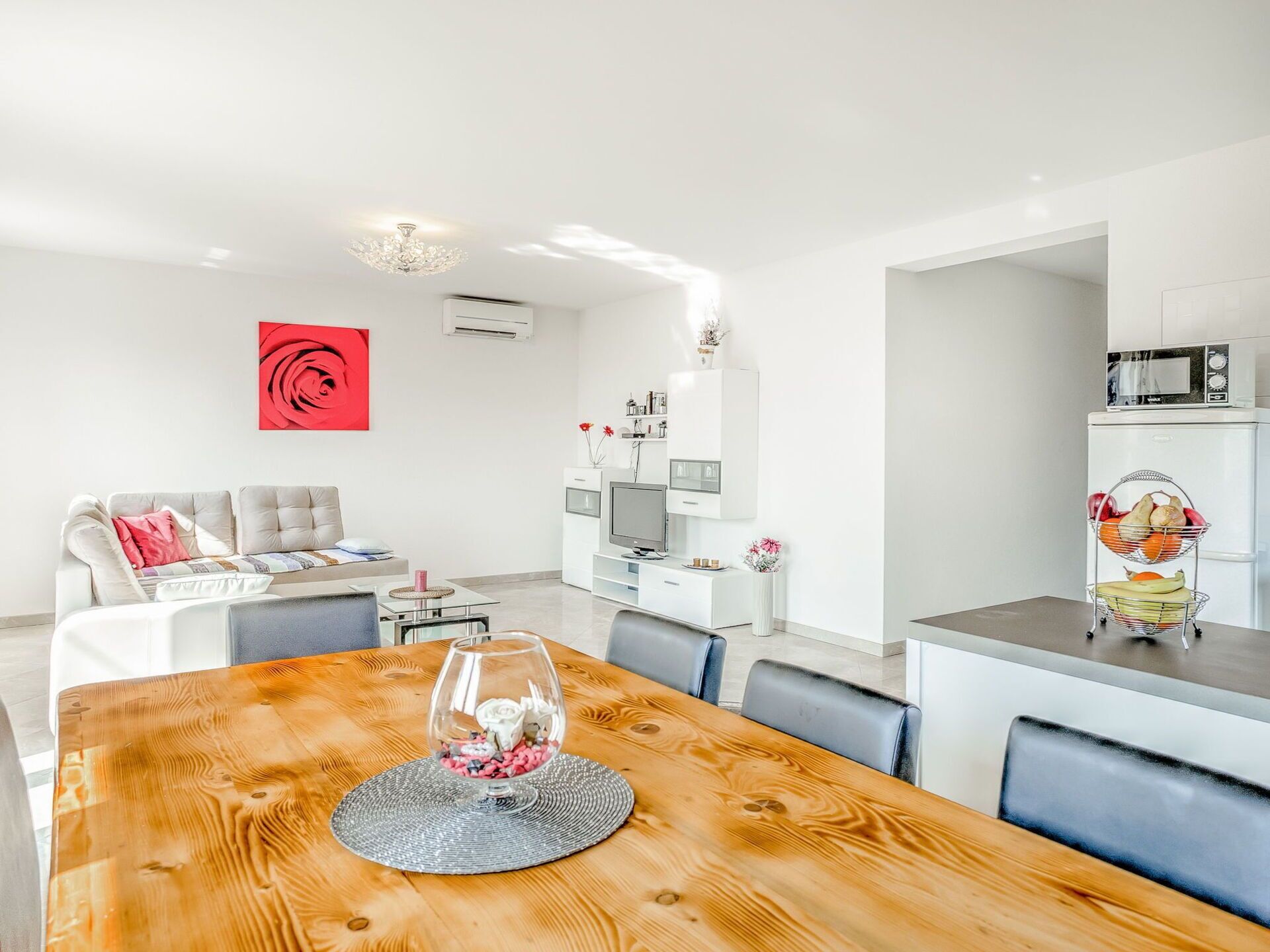 A modern living room with a wooden dining table, a sofa, and a kitchen area with a microwave.