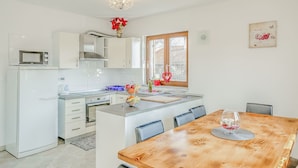 A modern kitchen with white cabinets, a microwave, and a dining area with a wooden table and chairs.
