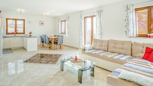 A modern living room with a sofa, a glass coffee table, and a dining area with a table and chairs.