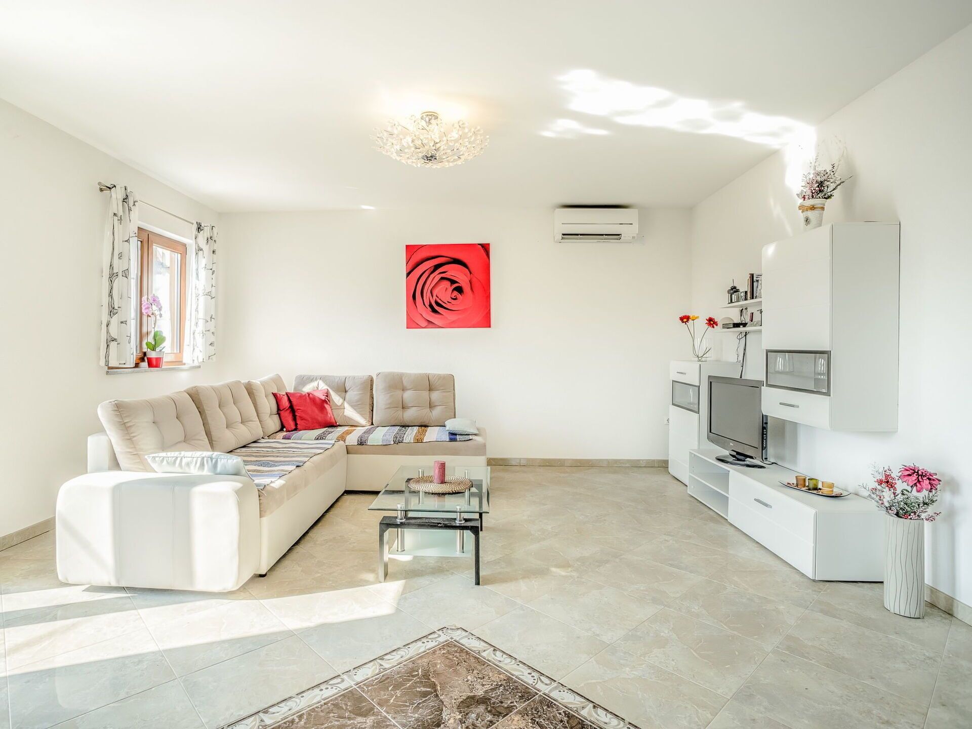 A modern living room with a sectional sofa, a glass coffee table, a flat-screen TV, and a decorative vase.