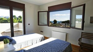 A bedroom with a bed, a table, a chair, a ceiling fan, and a window with a view of the sea. - Beautiful private villa for 8 guests with WIFI, private pool, TV, patio and pets allowed (L'ampolla)