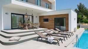 Uma casa moderna de dois andares com piscina, área de estar ao ar livre e espaço para refeições.