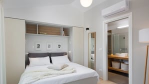 Um quarto moderno com uma cama grande, estantes embutidas, um closet espaçoso e um ar condicionado.