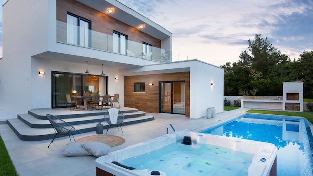 Uma casa moderna de dois andares com piscina e banheira de hidromassagem.
