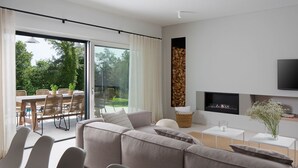 Uma sala de estar moderna com um sofá grande, uma área de jantar com mesa e cadeiras, e uma lareira.