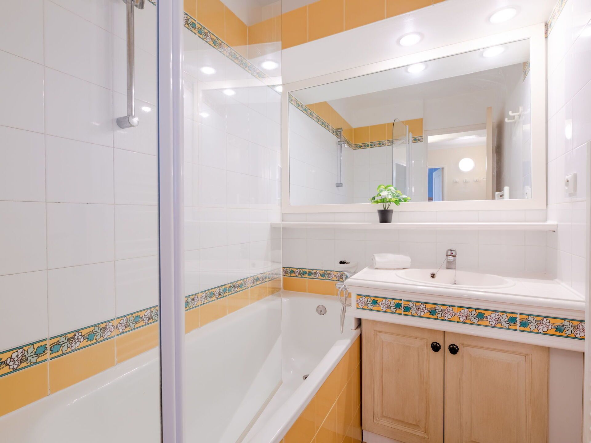 Une salle de bain avec une douche à parois de verre, une baignoire, un lavabo avec un miroir au-dessus et un meuble en bois.