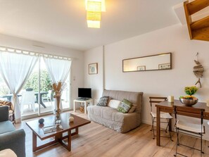 A modern living room with a sofa, coffee table, and dining table. There is a TV on a small table, and a window with curtains. - Stunning  villa for 4 guests with WIFI, TV, terrace and pets allowed (Mimizan)