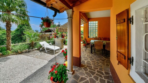 A covered patio area with a stone floor, a wooden ceiling, and a view of a lush garden. - Nice apartment for 6 guests with WIFI, A/C, TV, terrace and pets allowed (Rijeka)