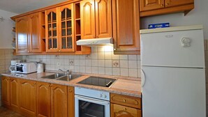 A kitchen with wooden cabinets, a built-in oven, a microwave, and a refrigerator. - Nice apartment for 6 guests with WIFI, A/C, TV, terrace and pets allowed (Rijeka)