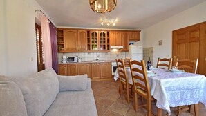 A cozy kitchen with wooden cabinets, a dining table set for four, and a modern microwave. - Nice apartment for 6 guests with WIFI, A/C, TV, terrace and pets allowed (Rijeka)