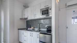 Een moderne keuken met witte kasten, een roestvrijstalen koelkast, een magnetron en een inbouwoven.