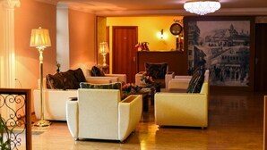 A hotel lobby with a classic design, featuring a seating area with armchairs and sofas, a chandelier, and a large painting on the wall. - Sanahin Bridge Hotel (Alaverdi)