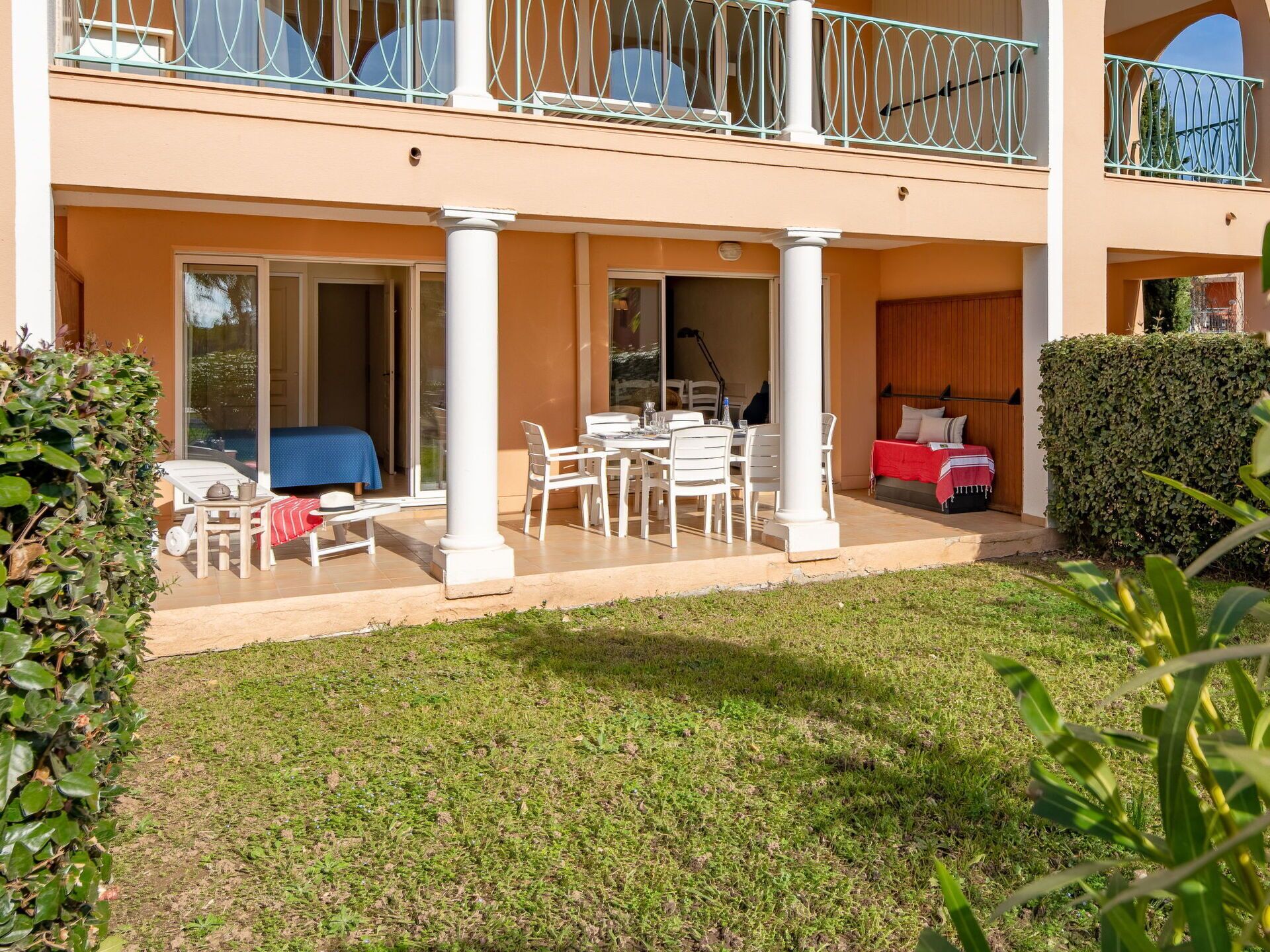 A two-story building with a covered patio area, a dining table with chairs, and a sofa.