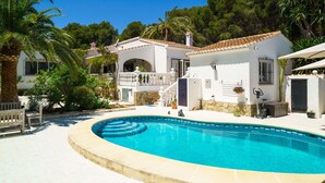 Blick auf eine Villa mit Pool, weißen Wänden und einem Ziegeldach.