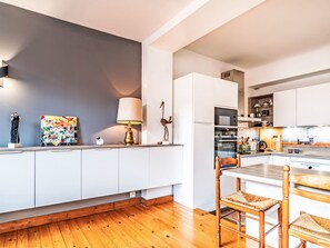 Eine moderne Küche mit weißen Schränken, Holzboden und einem Essbereich mit zwei Stühlen.