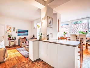 Eine moderne Küche mit weißen Schränken, einer Holztischinsel und einem Essbereich mit Stühlen und einem Tisch.