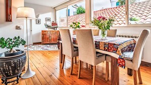 A dining area with a wooden table, chairs, and a vase of flowers.