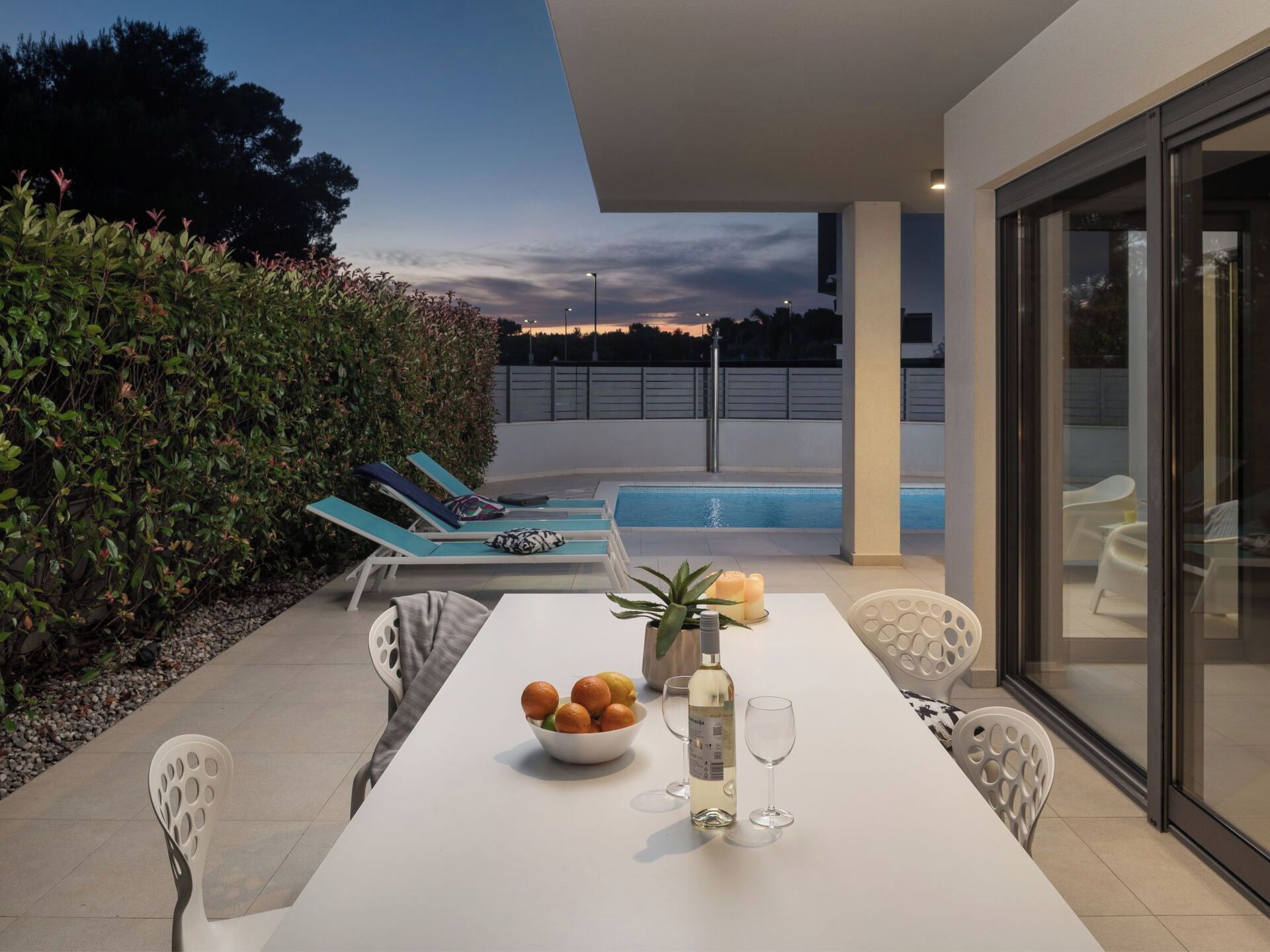 A modern outdoor dining area with a pool in the background.