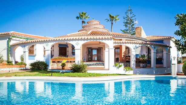 Un resort con piscina, un patio cubierto y un estilo arquitectónico tradicional.