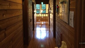 A wooden hallway with a bench, a door, and a window at the end.