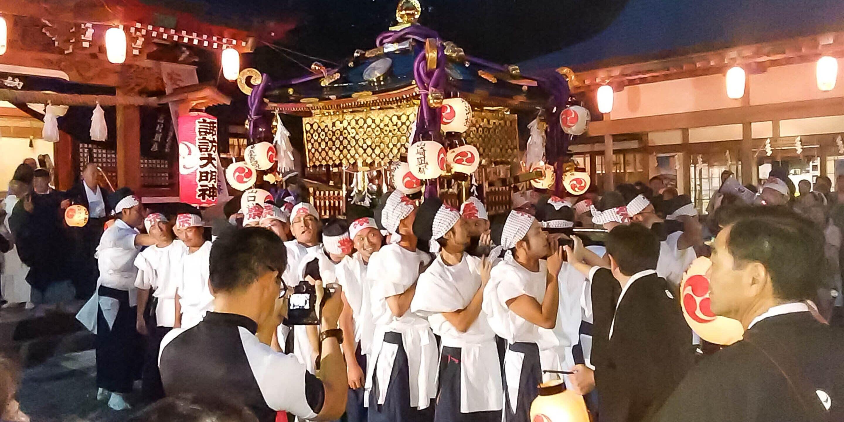 Un grupo de personas vestidas con atuendo tradicional reunido alrededor de una estructura decorada con techo dorado y faroles.