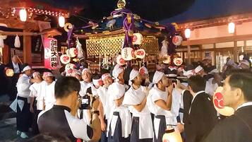 Un grupo de personas vestidas con atuendo tradicional reunido alrededor de una estructura decorada con techo dorado y faroles.