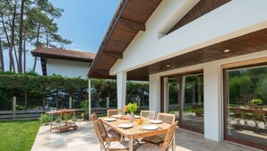 Une terrasse extérieure avec une table et des chaises, entourée d’un jardin et d’une clôture en bois.