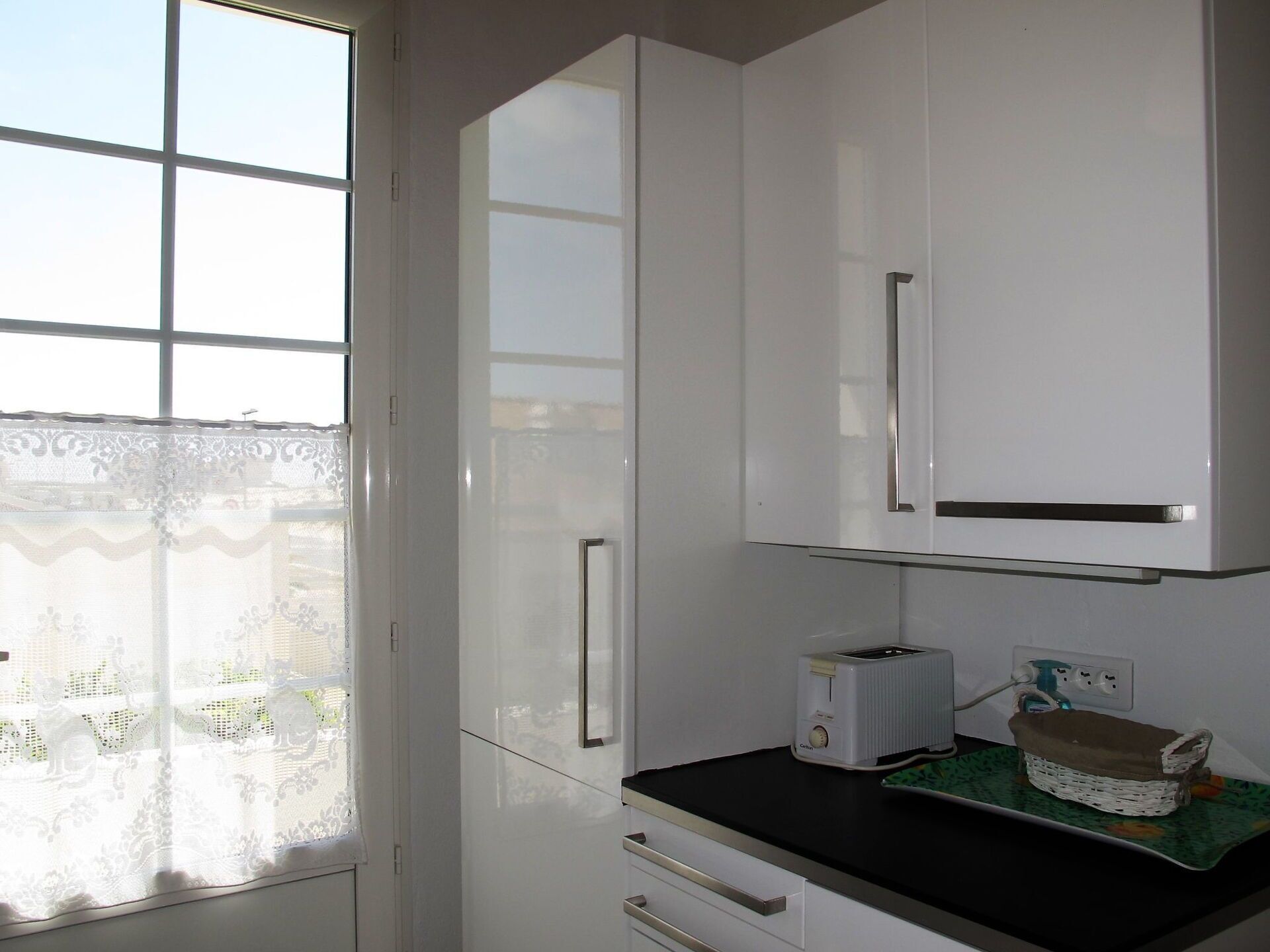 A kitchen with white cabinets, a toaster, and a wicker basket on the counter.