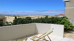 A balcony with two wooden beach chairs and a view of the beach and ocean. - Lovely apartment for 4 guests with WIFI, TV and terrace (Mimizan)