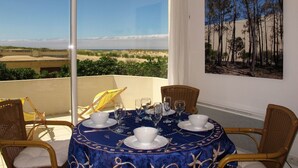 A balcony with a table set for four, overlooking a beach and dunes. - Lovely apartment for 4 guests with WIFI, TV and terrace (Mimizan)